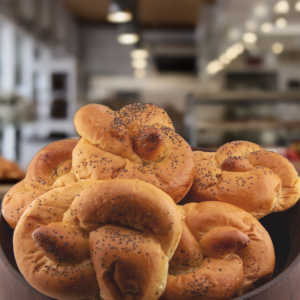 Freshly baked brioche egg bread buns with poppy seeds on top in a wooden bowl.