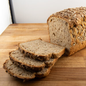 Loaf of sunflower rye bread sliced on a wooden cutting board